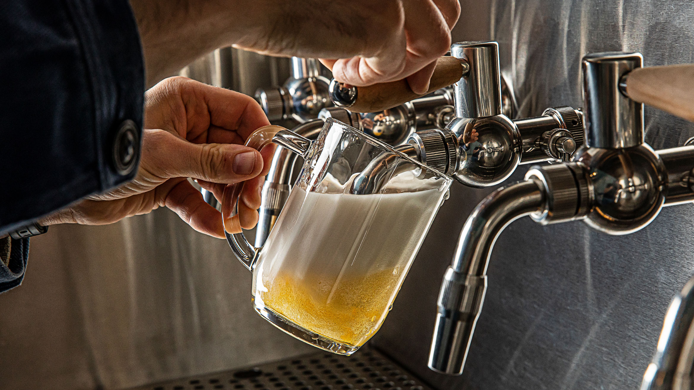 A person pours a beer from a tap into a mug. 