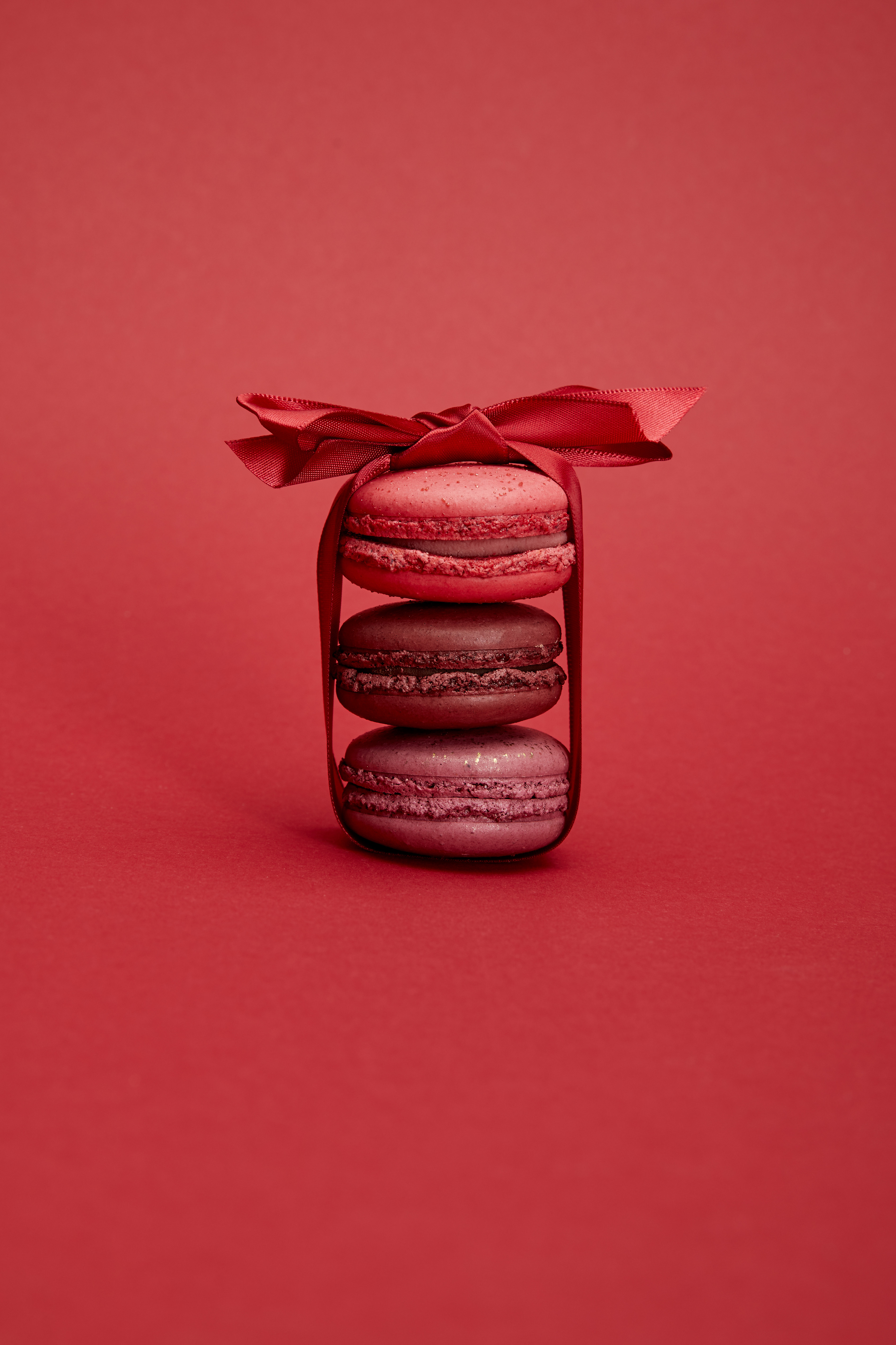 A trio of stacked macarons wrapped vertically with a red bow.