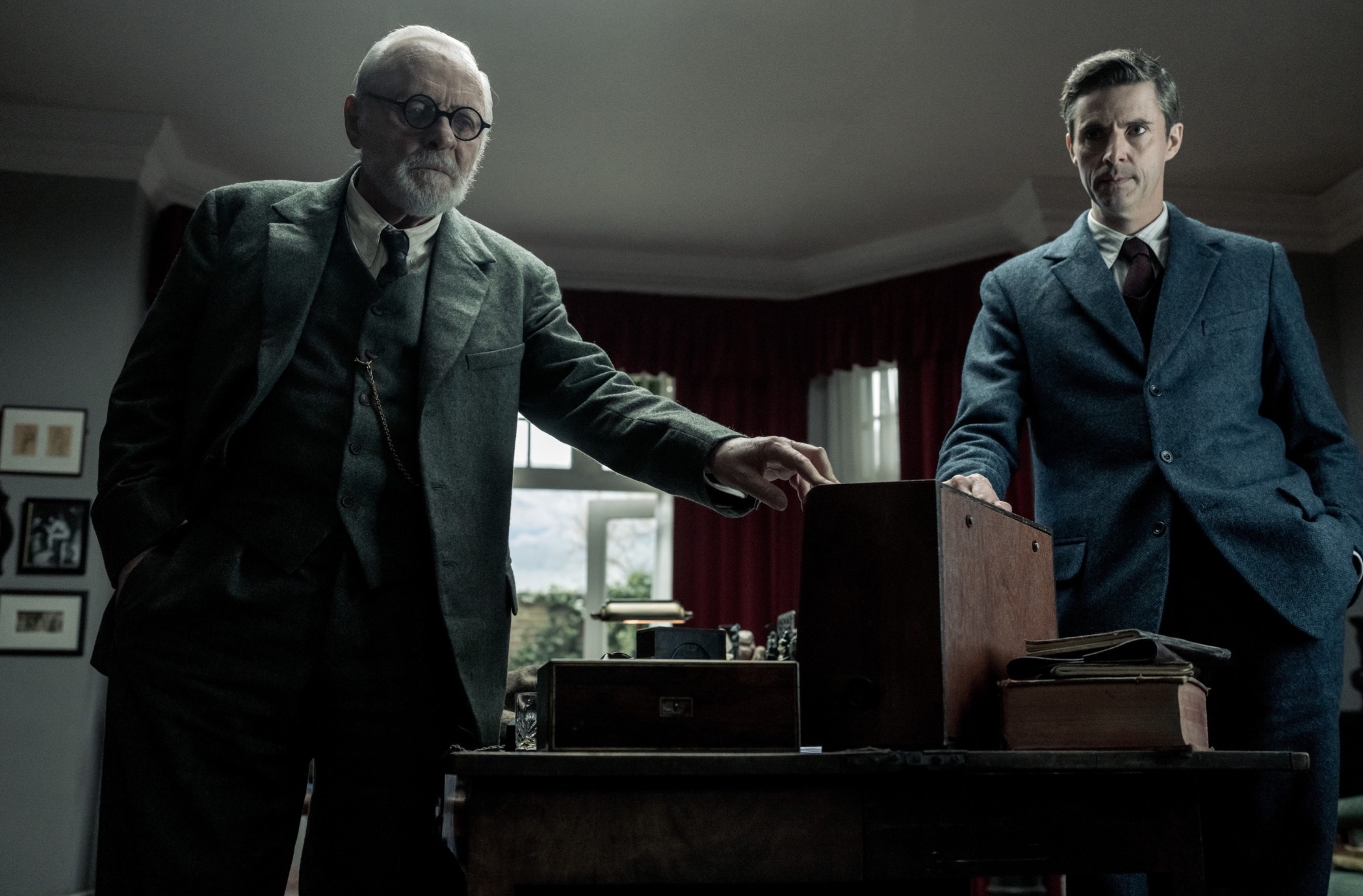 Freud (Anthony Hopkins) and CS Lewis (Matthew Goode) both touch a box in the middle of an old room in Freud’s Last Session