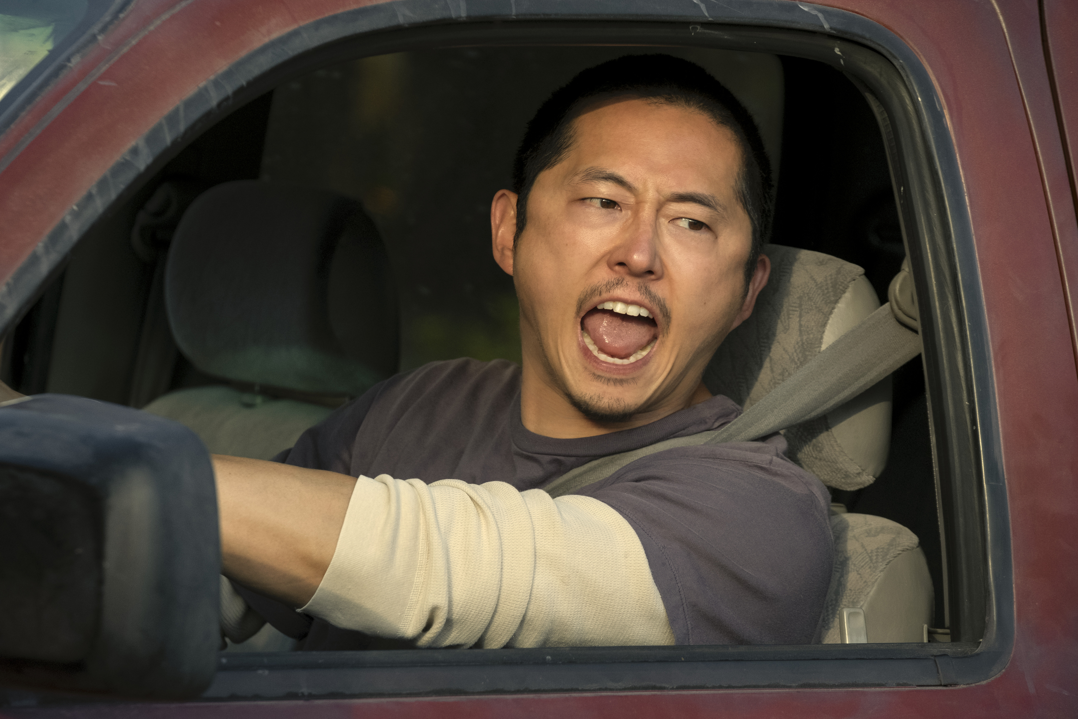 Steven Yeun yells while driving a red truck in Beef