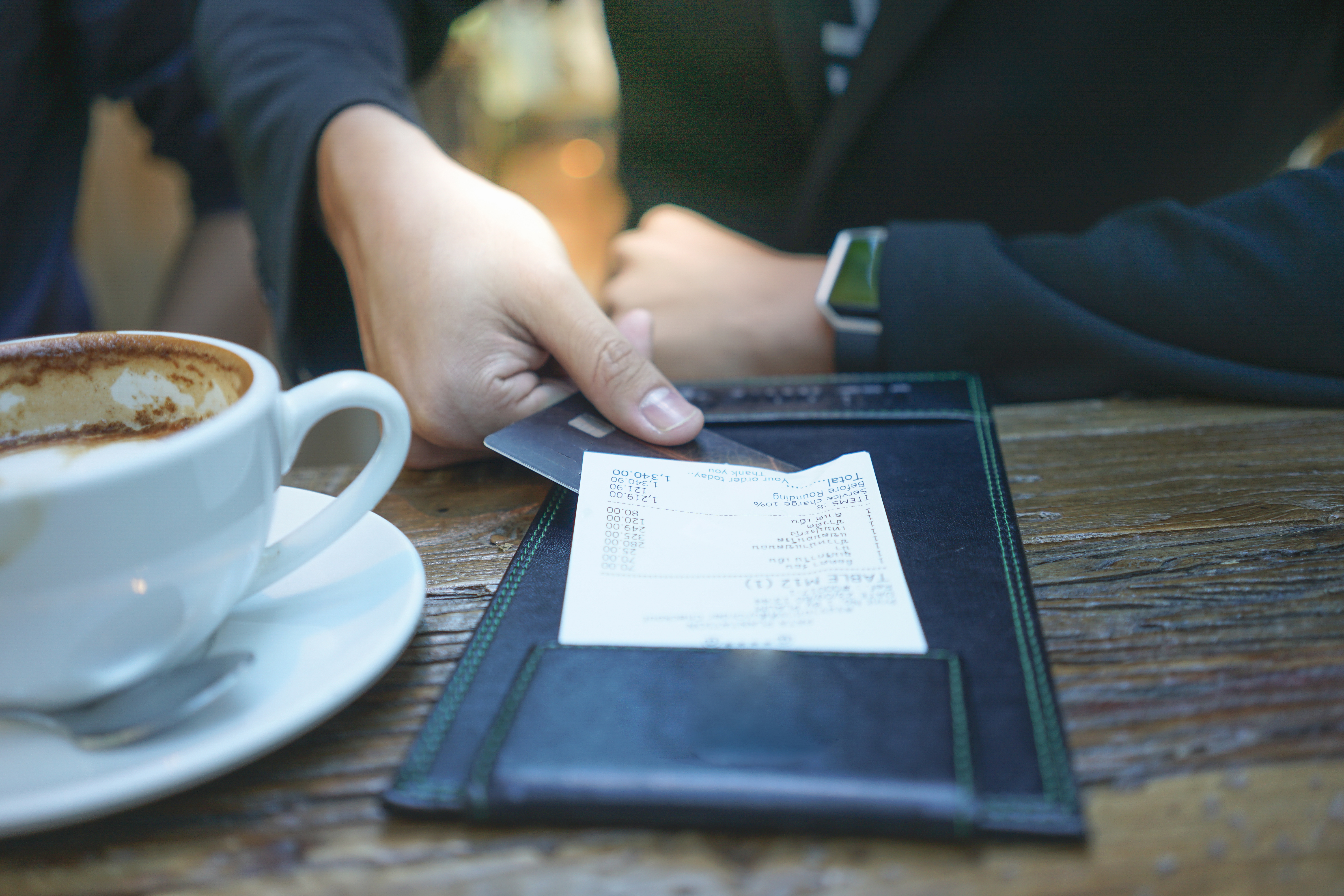 An image of a pair of hands holding a restaurant check.