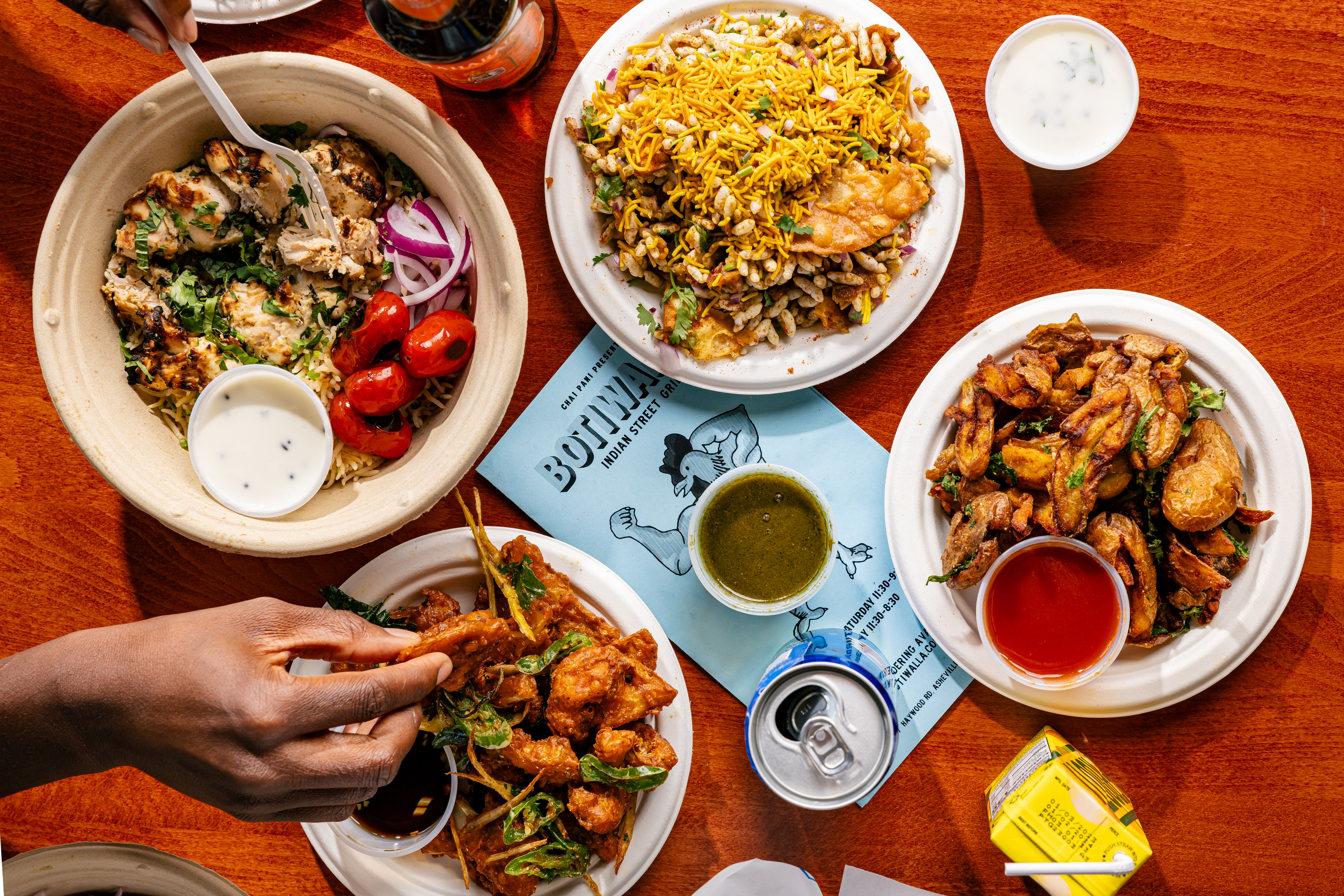 A shawarma bowl, chaat, and wings on a table. 