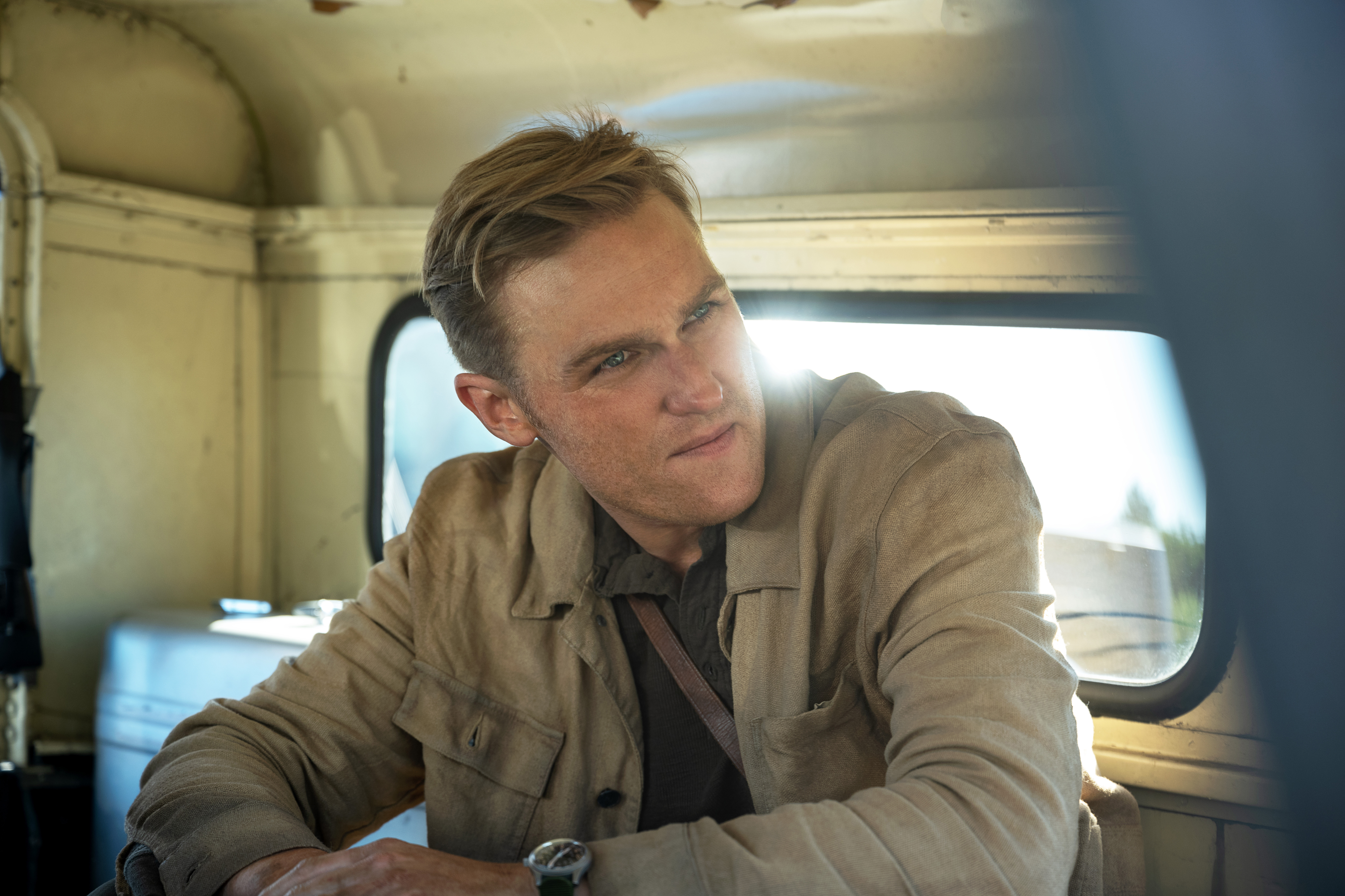 Wyatt Russell as Lee Shawm sitting in the back of a van looking softly interested in something