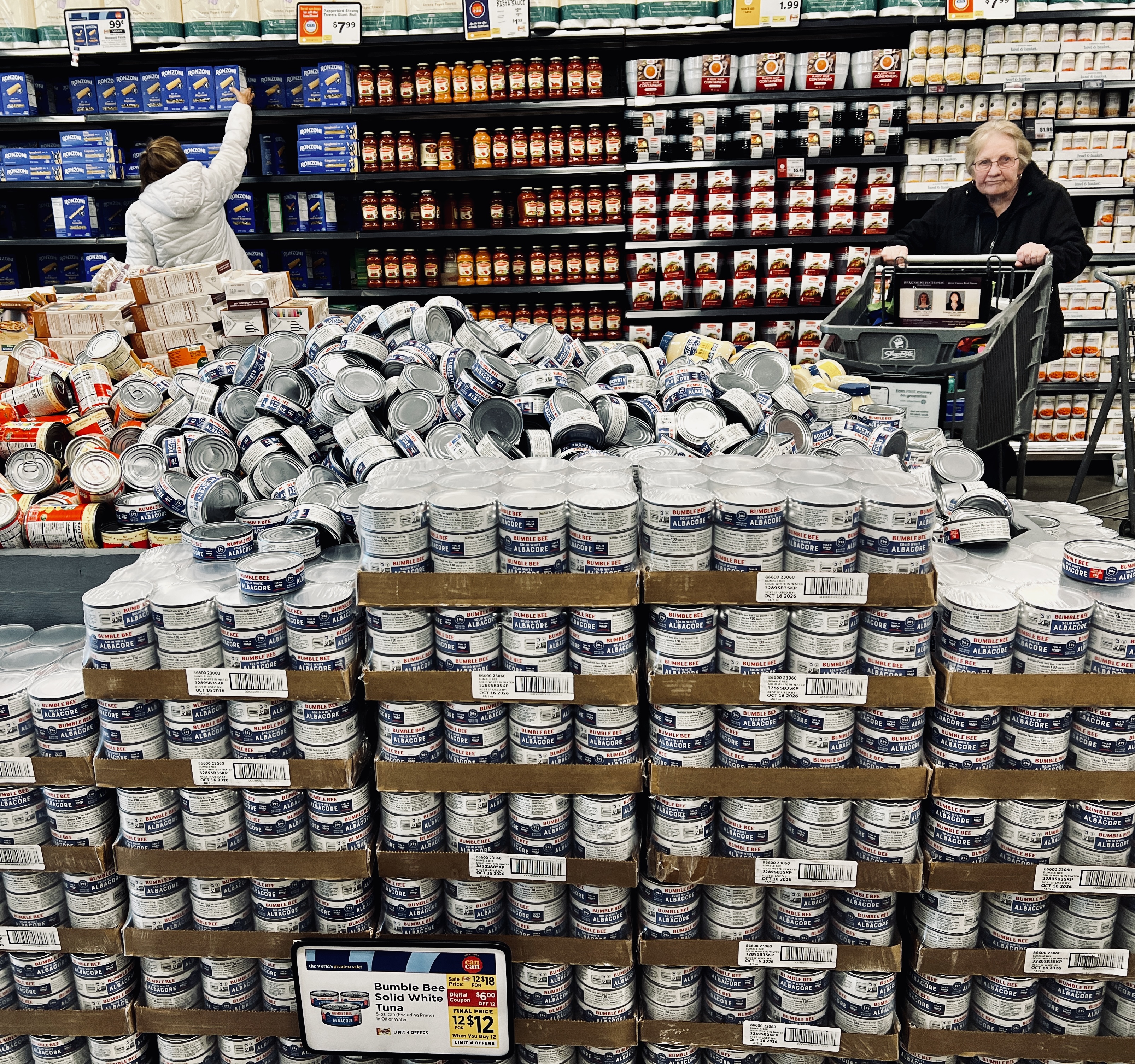 Piles of tuna cans in a grocery store.