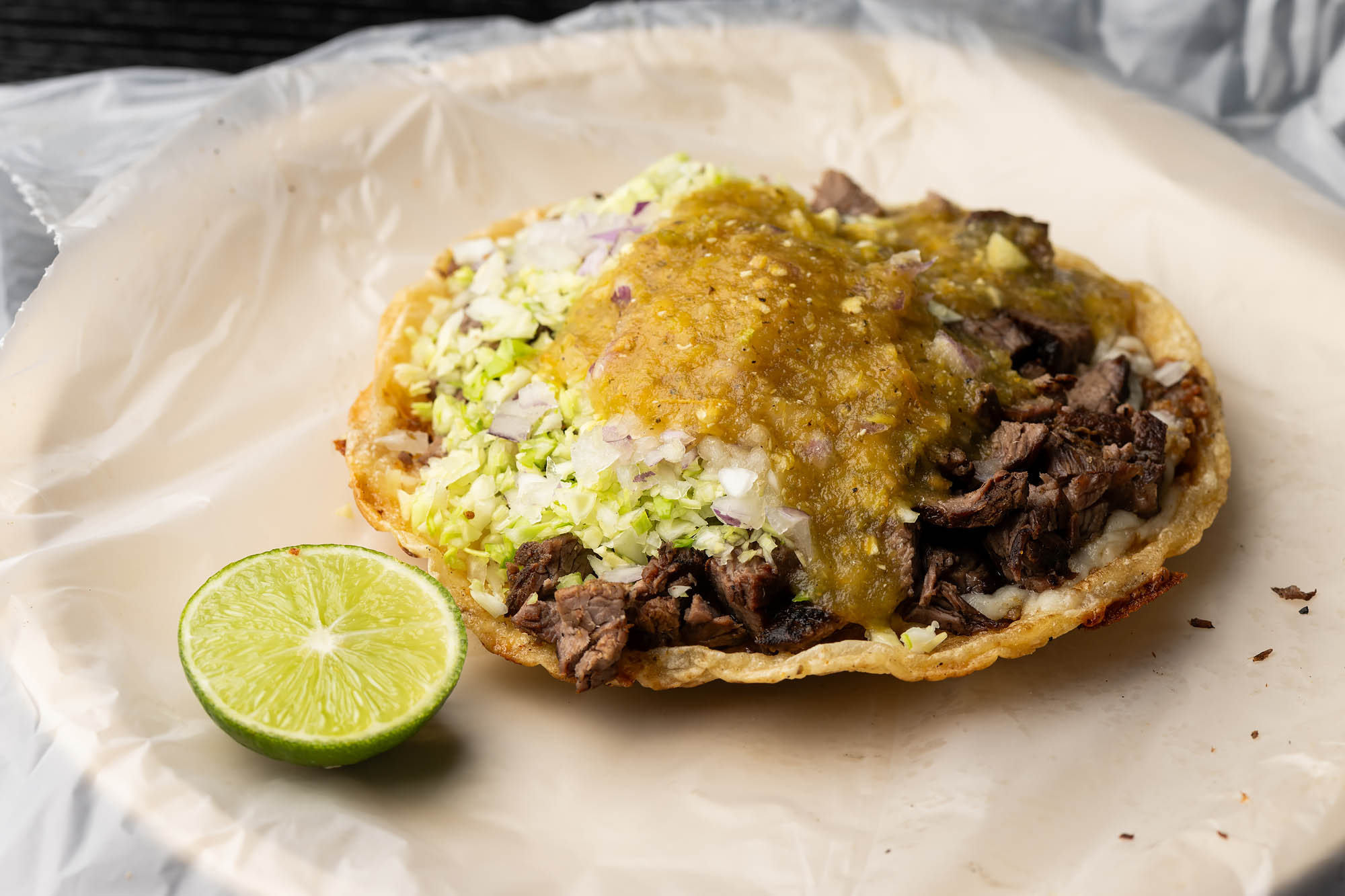 A grilled beef taco with a slice of lime.