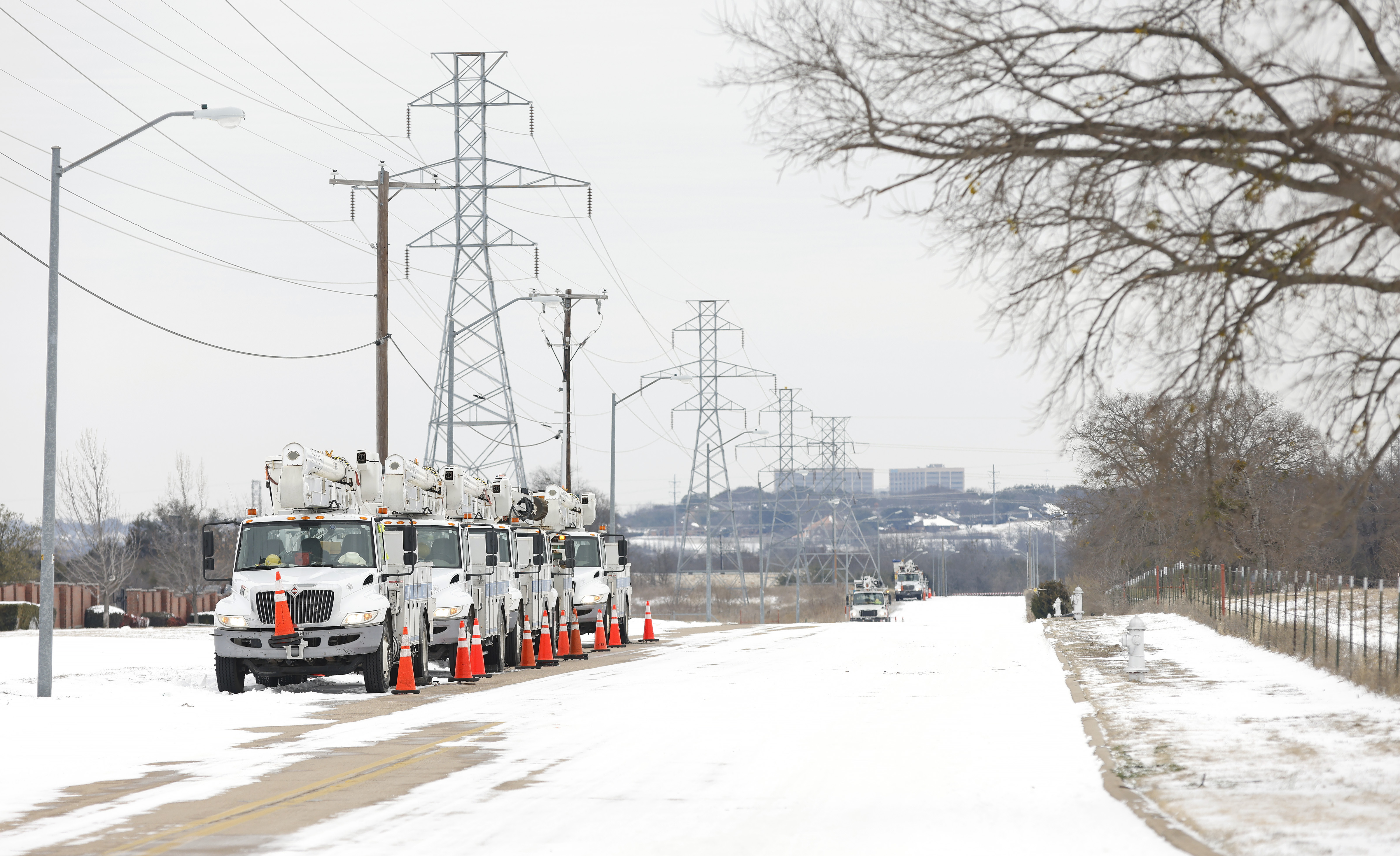 Electric utility service trucks line up after a snow storm along a snow-covered street on February 16, 2021, in Fort Worth, Texas.