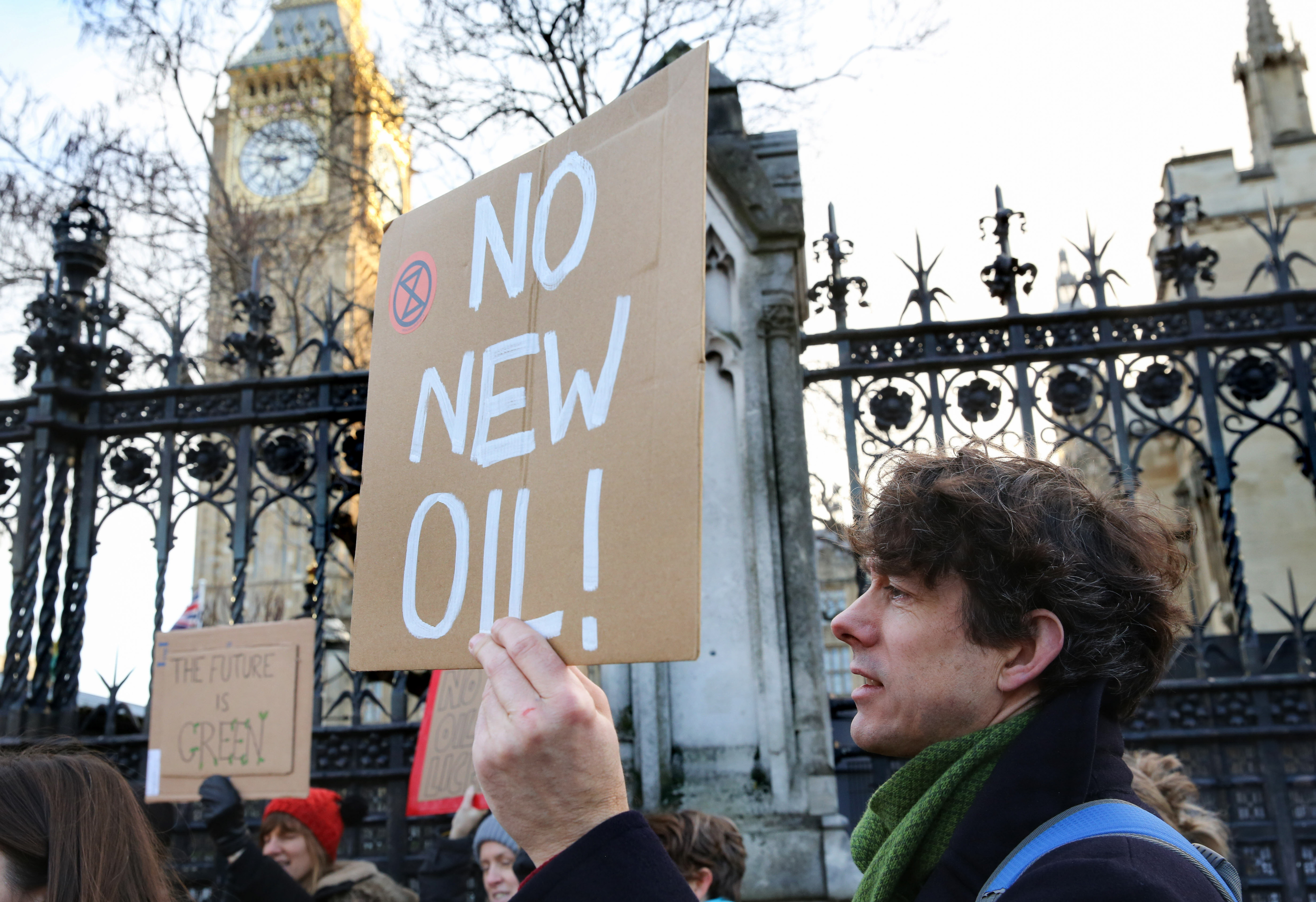 A protester holds a placard reading “No New Oil” outside the House of Parliament in London.