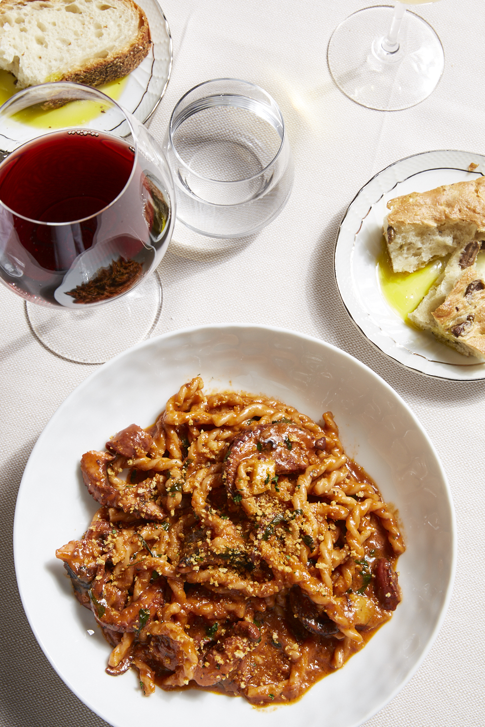 A plate of pasta, some bread, and wine.