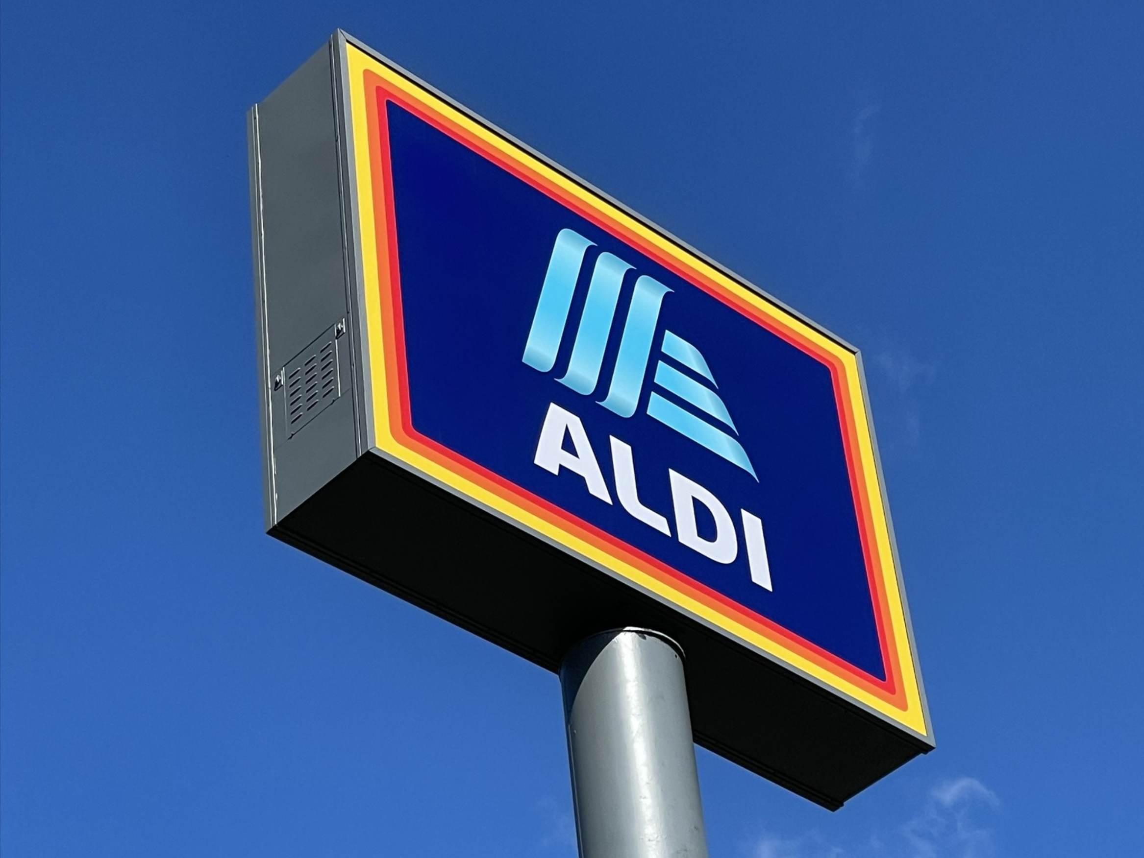 A sign for Aldi in front of a blue sky.