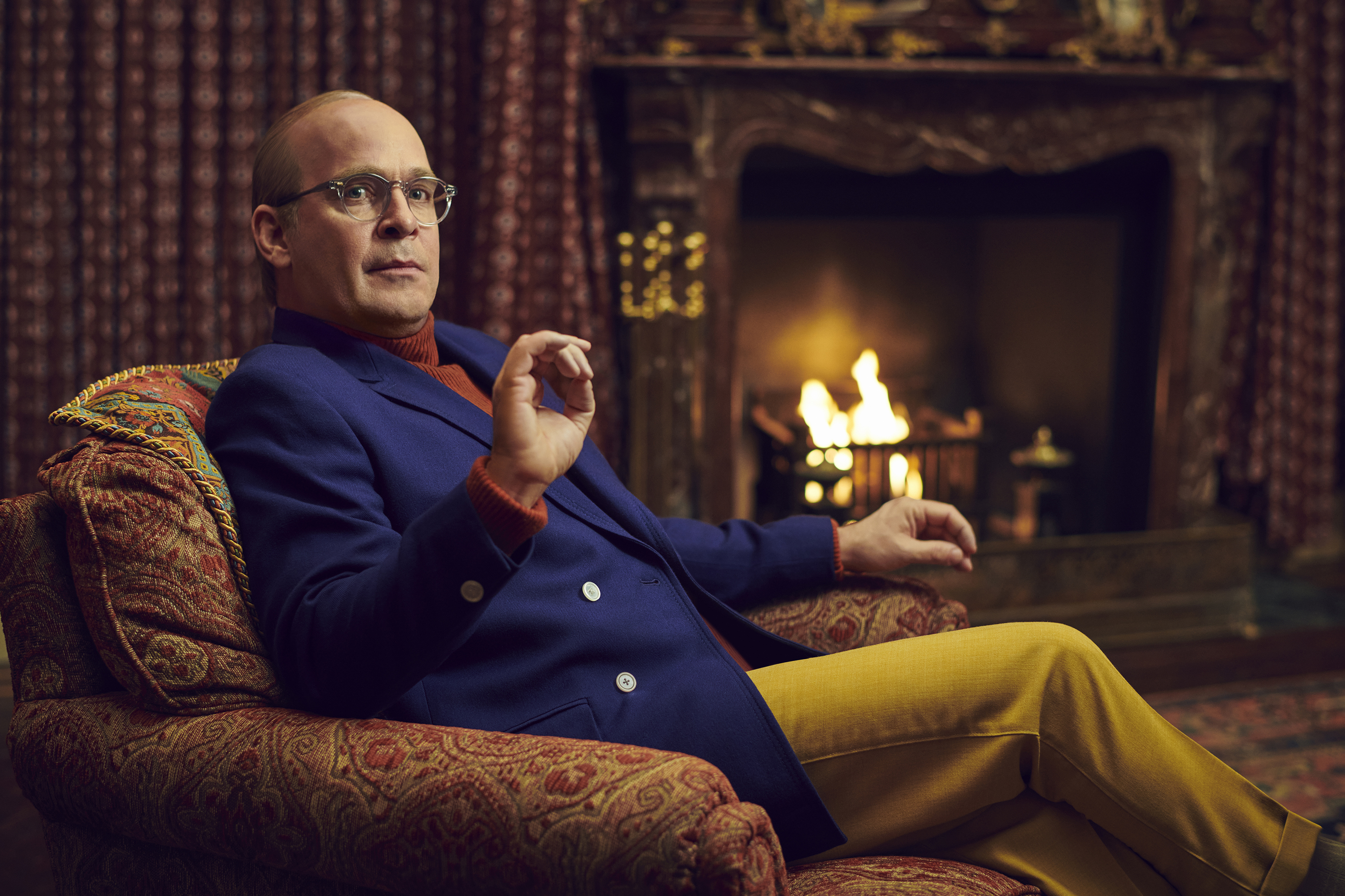 Tom Hollander as Truman Capote in a lounge chair, mustard slacks and a blue jacket from FX’s Feud: Capote vs. The Swans