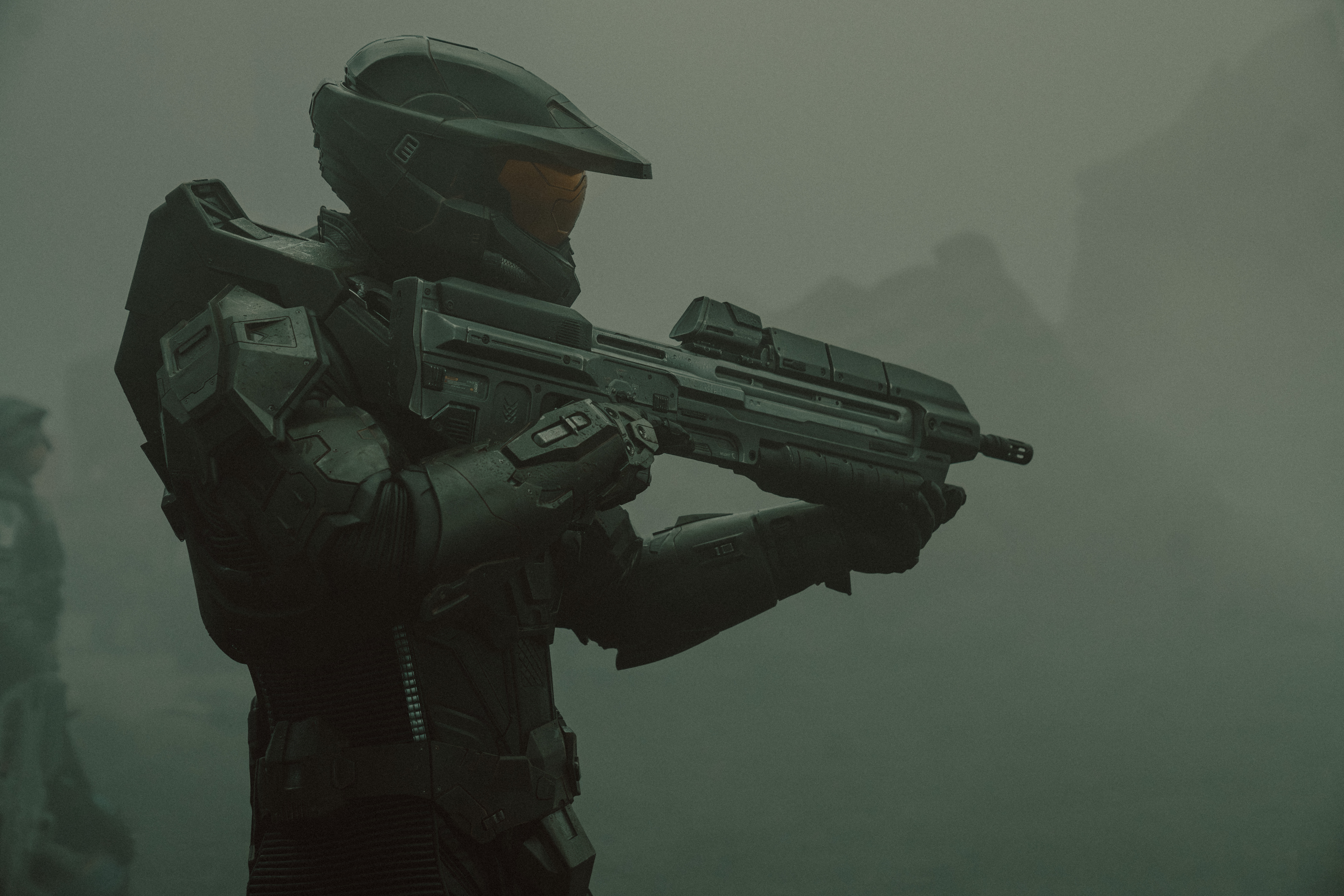Master Chief (Pablo Schreiber) standing and holding his plasma rifle