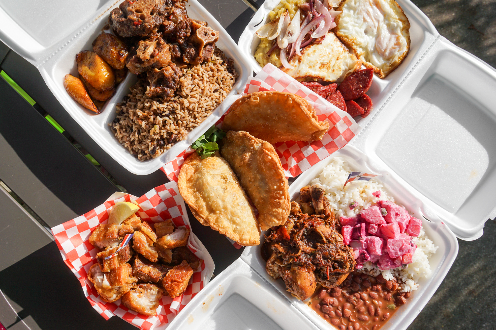 An overhead shot of takeout containers filled with Domincan food