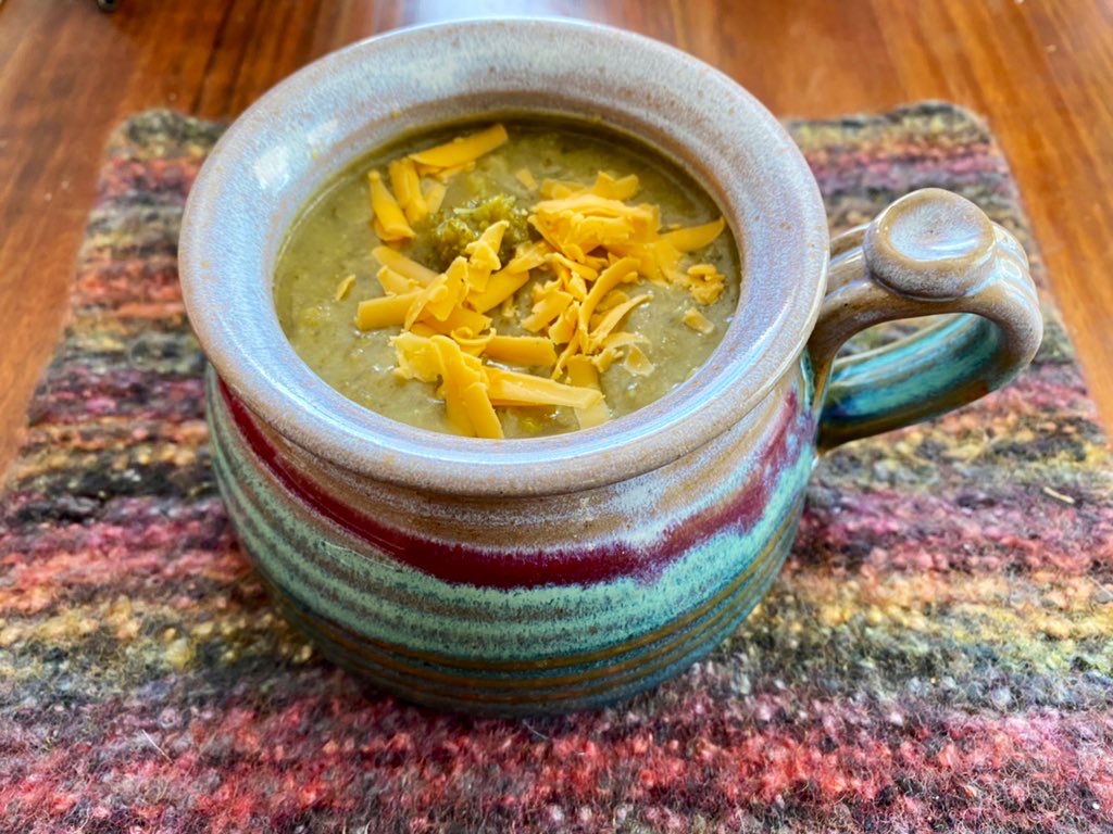 A colorful soup mug full of chunky soup.