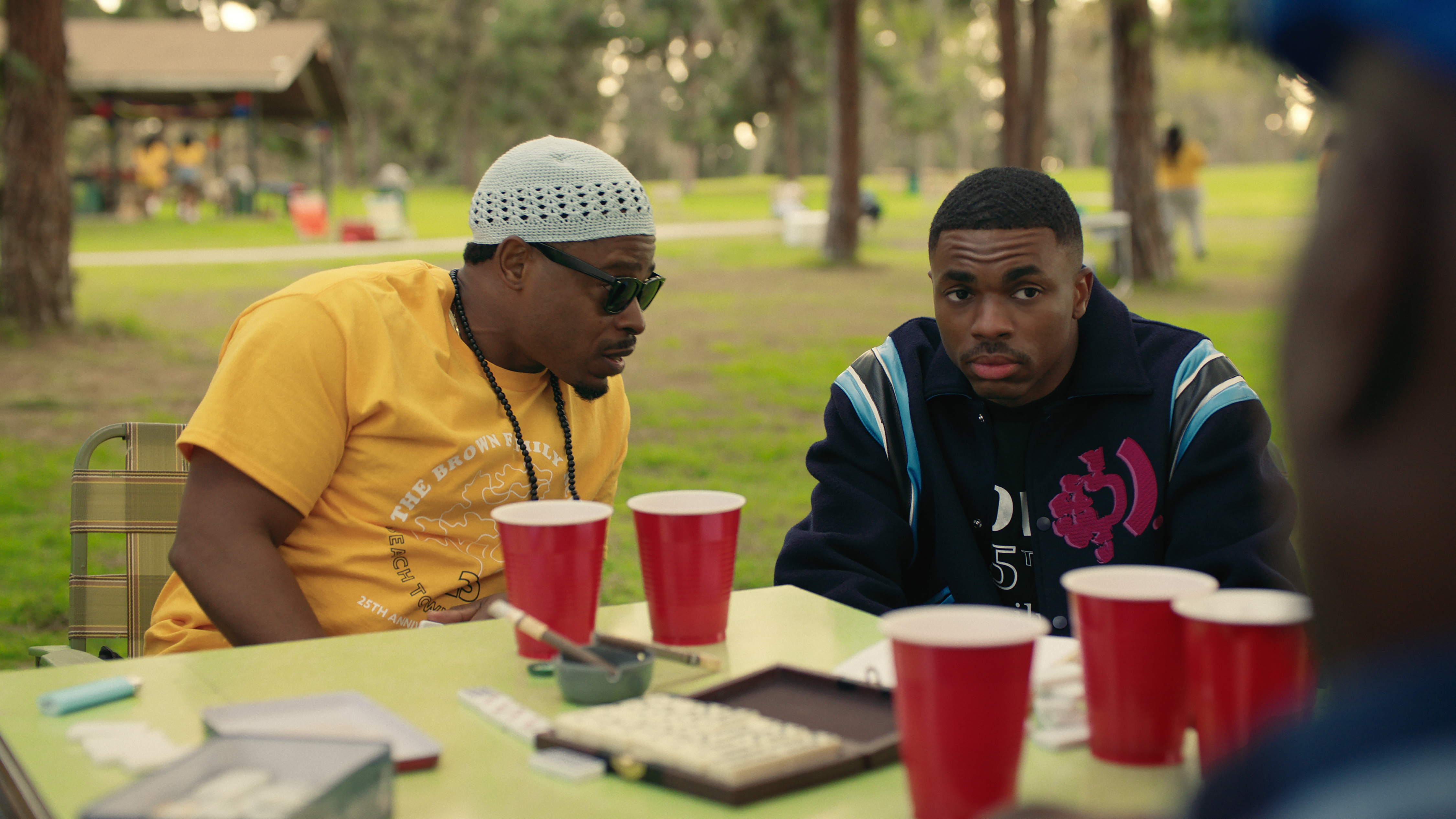 Kareem Grimes as Uncle Mike talking at a table in a park to Vince Staples as Vince Staples in a still from The Vince Staples Show