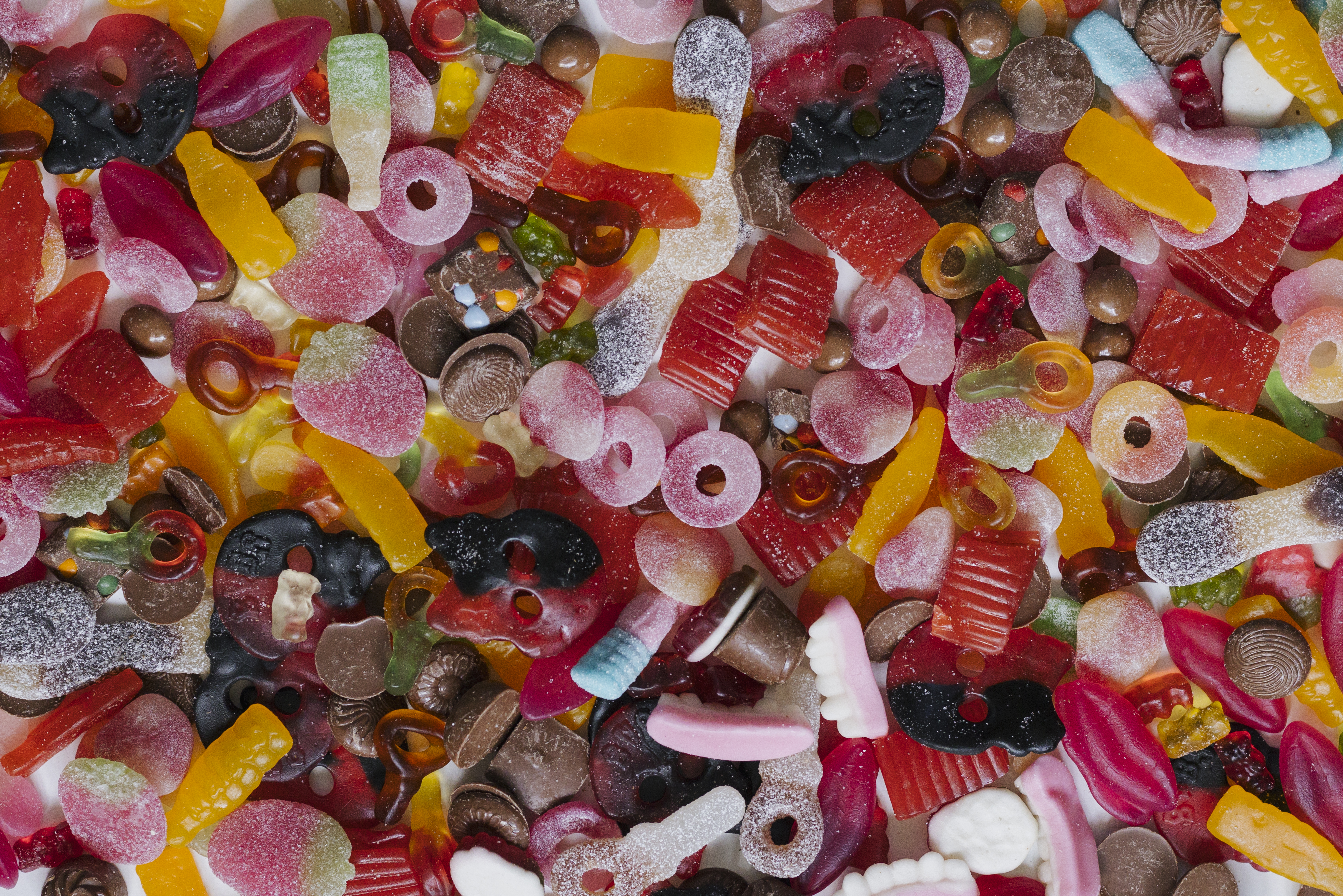 an overhead image of an assortment of colorful swedish candies including sweet and sour gummies and licorice