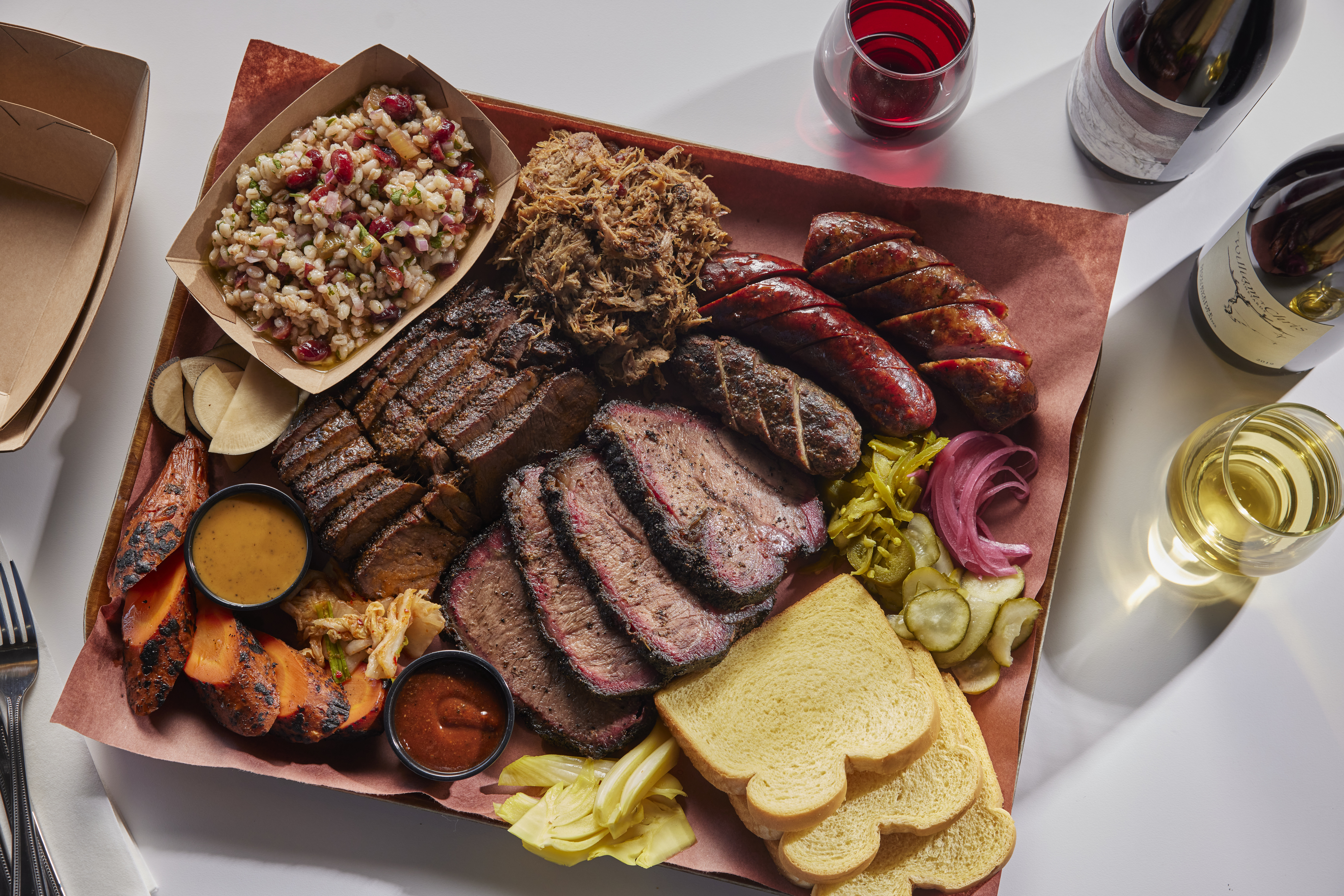 A tray with sliced meats, sides, and breads.