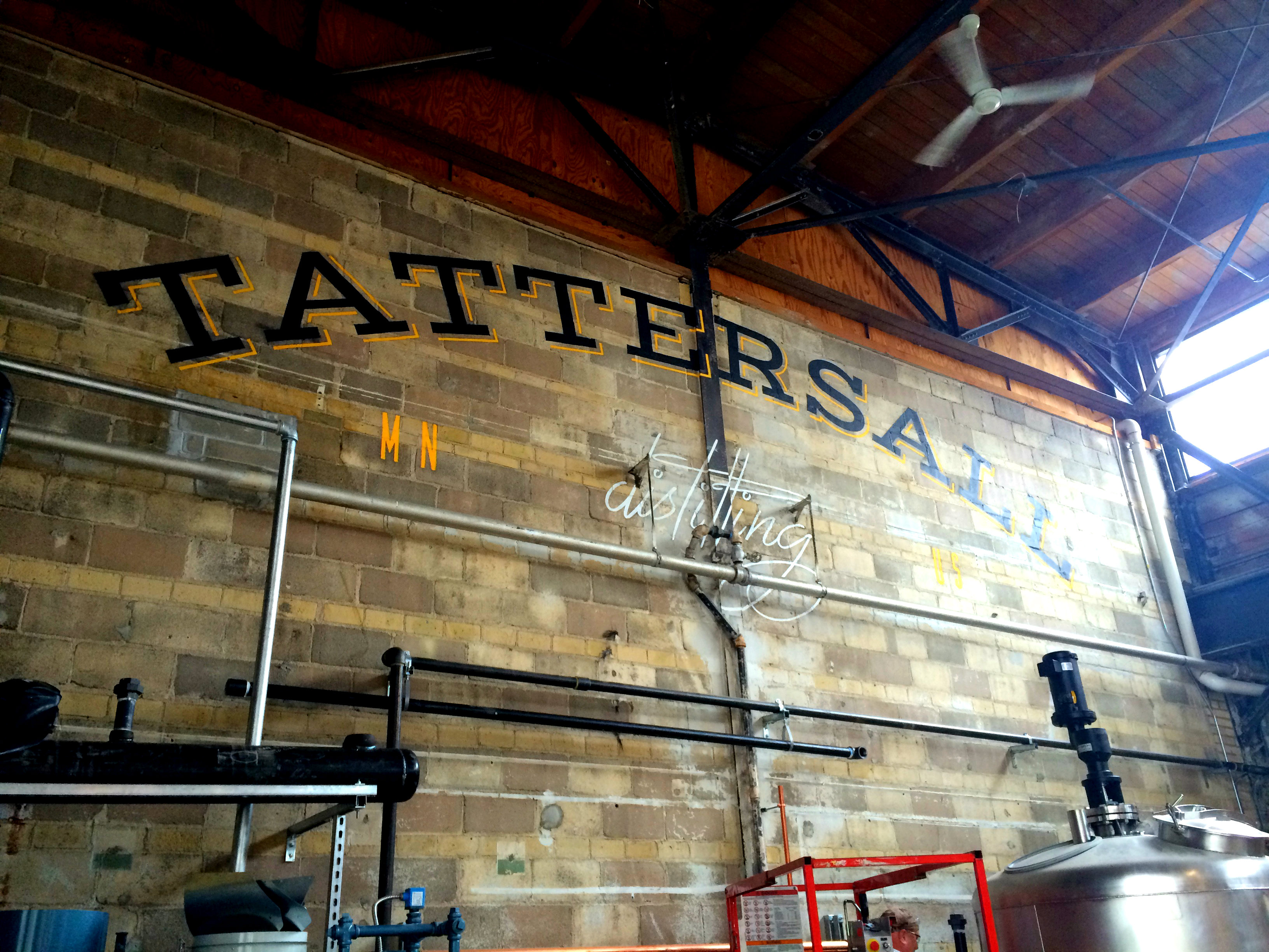 A brick wall with the words “Tattersall Distilling” painted across it.